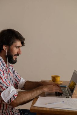Genç bir iş adamı evinde dizüstü bilgisayarla kahverengi bir koltukta çalışıyor. Çalışmak için gri defter. Merkez ofis konsepti. Yüksek kalite fotoğraf