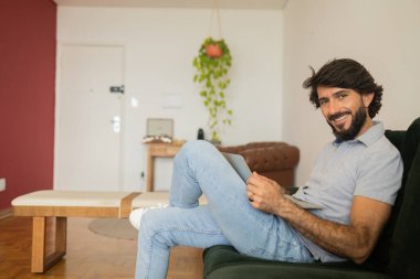 Oturma odasındaki kanepede dizüstü bilgisayarla çalışan genç bir iş adamı. Çalışmak için gri defter. Merkez ofis konsepti. Yüksek kalite fotoğraf