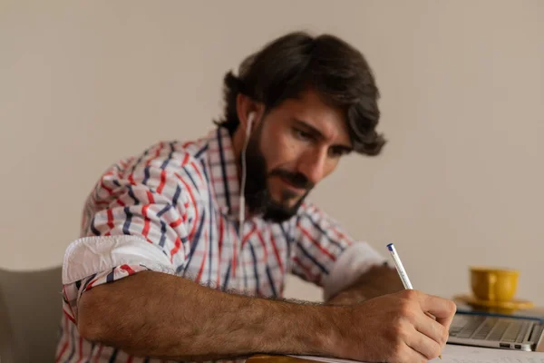 Genç bir iş adamı evinde dizüstü bilgisayarla kahverengi bir koltukta çalışıyor. Çalışmak için gri defter. Merkez ofis konsepti. Yüksek kalite fotoğraf