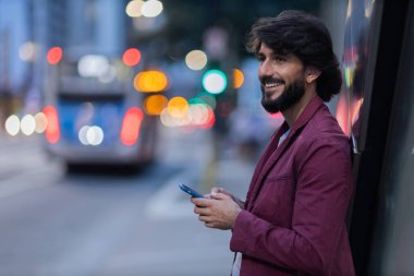 Gece vakti arka planda şehir manzarası olan akıllı telefon kullanan genç bir adamın görüntüsü. Cep telefonu, teknoloji, şehir konsepti. Yüksek kalite fotoğraf