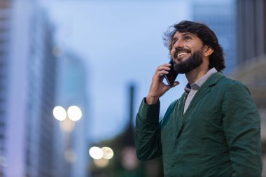 Gece vakti arka planda şehir manzarası olan akıllı telefon kullanan genç bir adamın görüntüsü. Cep telefonu, teknoloji, şehir konsepti. Yüksek kalite fotoğraf