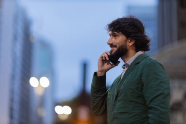 Gece vakti arka planda şehir manzarası olan akıllı telefon kullanan genç bir adamın görüntüsü. Cep telefonu, teknoloji, şehir konsepti. Yüksek kalite fotoğraf