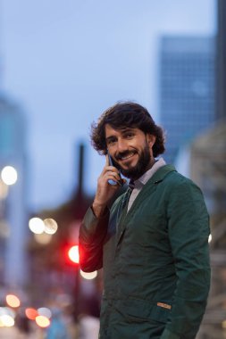 Gece vakti arka planda şehir manzarası olan akıllı telefon kullanan genç bir adamın görüntüsü. Cep telefonu, teknoloji, şehir konsepti. Yüksek kalite fotoğraf