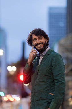 Gece vakti arka planda şehir manzarası olan akıllı telefon kullanan genç bir adamın görüntüsü. Cep telefonu, teknoloji, şehir konsepti. Yüksek kalite fotoğraf