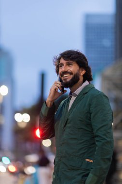 Gece vakti arka planda şehir manzarası olan akıllı telefon kullanan genç bir adamın görüntüsü. Cep telefonu, teknoloji, şehir konsepti. Yüksek kalite fotoğraf