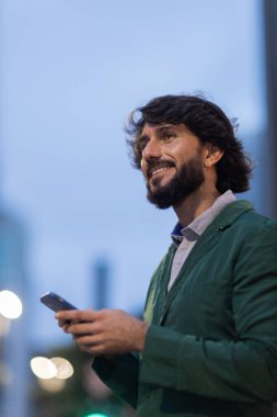 Gece vakti arka planda şehir manzarası olan akıllı telefon kullanan genç bir adamın görüntüsü. Cep telefonu, teknoloji, şehir konsepti. Yüksek kalite fotoğraf