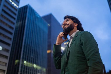 Gece vakti arka planda şehir manzarası olan akıllı telefon kullanan genç bir adamın görüntüsü. Cep telefonu, teknoloji, şehir konsepti. Yüksek kalite fotoğraf