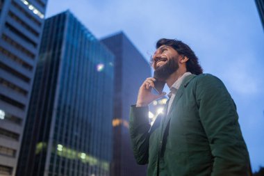 Gece vakti arka planda şehir manzarası olan akıllı telefon kullanan genç bir adamın görüntüsü. Cep telefonu, teknoloji, şehir konsepti. Yüksek kalite fotoğraf