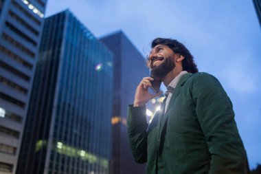 Gece vakti arka planda şehir manzarası olan akıllı telefon kullanan genç bir adamın görüntüsü. Cep telefonu, teknoloji, şehir konsepti. Yüksek kalite fotoğraf