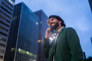 Gece vakti arka planda şehir manzarası olan akıllı telefon kullanan genç bir adamın görüntüsü. Cep telefonu, teknoloji, şehir konsepti. Yüksek kalite fotoğraf