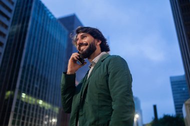 Gece vakti arka planda şehir manzarası olan akıllı telefon kullanan genç bir adamın görüntüsü. Cep telefonu, teknoloji, şehir konsepti. Yüksek kalite fotoğraf