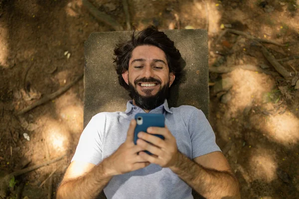 Vista Joven Usando Teléfono Inteligente Durante Día Acostado Banco Parque — Foto de Stock