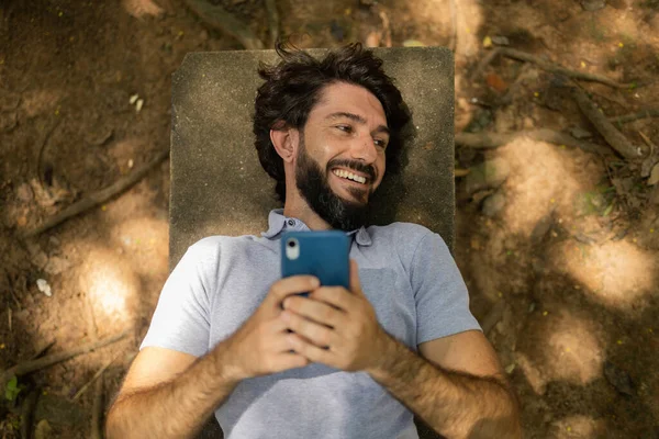 Vista Joven Usando Teléfono Inteligente Durante Día Acostado Banco Parque — Foto de Stock