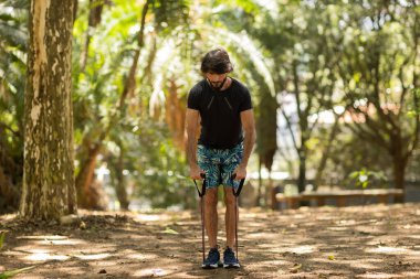 Parkta lastik bantlarla çalışan güçlü bir adam. Spor yaparken spor malzemeleriyle spor yapan erkek sporcu. Yüksek kalite fotoğraf. İyi, sağlıklı, sağlık, egzersiz konsepti. 