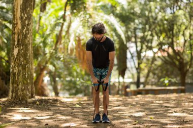 Parkta lastik bantlarla çalışan güçlü bir adam. Spor yaparken spor malzemeleriyle spor yapan erkek sporcu. Yüksek kalite fotoğraf. İyi, sağlıklı, sağlık, egzersiz konsepti. 