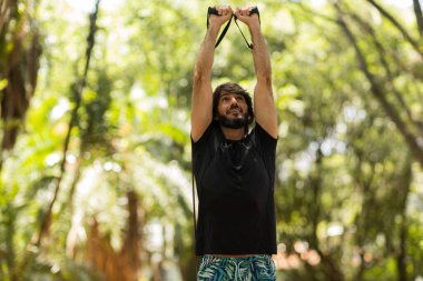 Parkta lastik bantlarla çalışan güçlü bir adam. Spor yaparken spor malzemeleriyle spor yapan erkek sporcu. Yüksek kalite fotoğraf. İyi, sağlıklı, sağlık, egzersiz konsepti. 