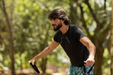 Parkta lastik bantlarla çalışan güçlü bir adam. Spor yaparken spor malzemeleriyle spor yapan erkek sporcu. Yüksek kalite fotoğraf. İyi, sağlıklı, sağlık, egzersiz konsepti. 