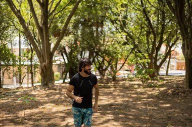 Genç bir adam parkta koşuyor ve koşuyor. Spor yaparken sporcu erkek. İyi, sağlıklı bir konsept. Yüksek kalite fotoğraf