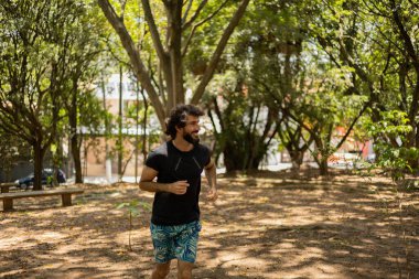 Genç bir adam parkta koşuyor ve koşuyor. Spor yaparken sporcu erkek. İyi, sağlıklı bir konsept. Yüksek kalite fotoğraf