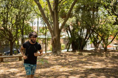 Genç bir adam parkta koşuyor ve koşuyor. Spor yaparken sporcu erkek. İyi, sağlıklı bir konsept. Yüksek kalite fotoğraf