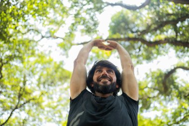 Genç bir adam parktaki antrenmandan önce esneme hareketleri yapıyor. Sporcu erkek sporcu antrenmana hazırlanıyor. İyi, sağlıklı bir konsept. Yüksek kalite çekim