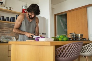 Mutfakta vejetaryen yemeği hazırlayan mutlu ve sağlıklı genç adam yemeği. Yüksek kalite fotoğraf. İyi, sağlıklı ve sağlıklı hissediyorum.. 