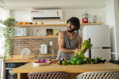 Mutfakta vejetaryen yemeği hazırlayan mutlu ve sağlıklı genç adam yemeği. Yüksek kalite fotoğraf. İyi, sağlıklı ve sağlıklı hissediyorum.. 