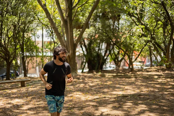 Genç bir adam parkta koşuyor ve koşuyor. Spor yaparken sporcu erkek. İyi, sağlıklı bir konsept. Yüksek kalite fotoğraf