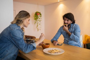 Birbirine aşık genç bir çift çok sağlıklı bir guacamole salatası yiyor ve bütün tostu mutfakta yiyor. Yüksek kalite fotoğraf. Yiyecek konsepti
