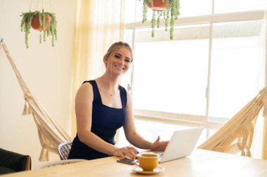 Mutfakta dizüstü bilgisayarı ve mutfak masasında kağıtlarıyla çalışan genç bir kadın. Merkez ofis konsepti. Çalışmak için gri defter. Merkez ofis konsepti. Yüksek kalite fotoğraf