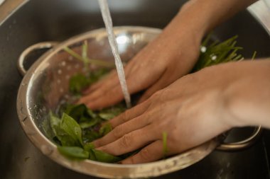 Mutfakta vejetaryen yemeği hazırlayan mutlu ve sağlıklı genç kadın yemeği. Yaprakları yıkıyorum. Yapraklı salata. Yüksek kalite fotoğraf. İyi, sağlıklı ve sağlıklı hissediyorum.. 