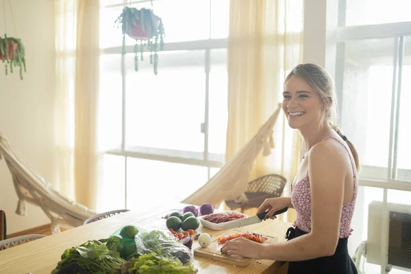 Happy and healthy young woman meal prepping whole vegetarian meal in the kitchen. High quality photo. Feel good, healthy and health concept.