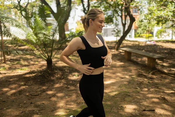 Genç bir kadın parkta koşuyor ve koşuyor. Spor yaparken bayan sporcu. İyi, sağlıklı bir konsept. Yüksek kalite fotoğraf