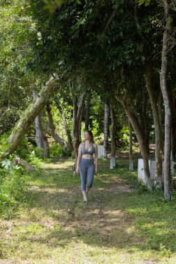 Güzel, güneşli bir günde parkta egzersiz yapan mutlu kadın. Kadın spor yapıyor. Yeşil ve doğa geçmişi. Yüksek kalite fotoğraf