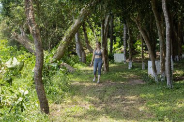 Güzel, güneşli bir günde parkta egzersiz yapan mutlu kadın. Kadın spor yapıyor. Yeşil ve doğa geçmişi. Yüksek kalite fotoğraf