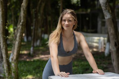 Güzel, güneşli bir günde parkta egzersiz yapan mutlu kadın. Kadın spor yapıyor. Yeşil ve doğa geçmişi. Yüksek kalite fotoğraf