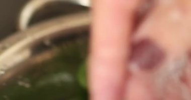 Mutfakta vejetaryen yemeği hazırlayan mutlu ve sağlıklı genç kadın yemeği. Yaprakları yıkıyorum. Yapraklı salata. Yüksek kaliteli video. İyi, sağlıklı ve sağlıklı hissediyorum..