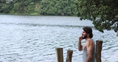 Yeşil bir parkta akıllı telefonuyla çalışan genç bir iş adamı. Merkez ofis konsepti, Mobile. Yüksek kaliteli video