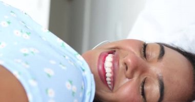 Genç siyahi kadın yatağında evinde kulaklıkla müzik dinliyor. İyi bir konsept, mutlu. Yüksek kaliteli video.