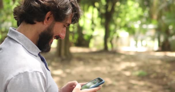 年轻的商人拿着智能手机在一个绿地公园里干活 总部的概念 高质量的录像 — 图库视频影像