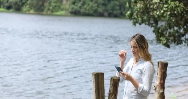 年轻的白人妇女在白天使用智能手机 背后有一个绿色的公园 高质量的视频 移动电话 城市概念 — 图库视频影像