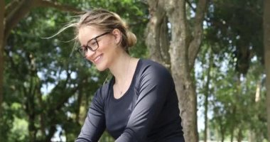 Genç beyaz kadın gündüz dizüstü bilgisayar kullanıyor ve arka planında yeşil bir park var. Yüksek kaliteli video. Mobil, teknoloji, şehir konsepti.