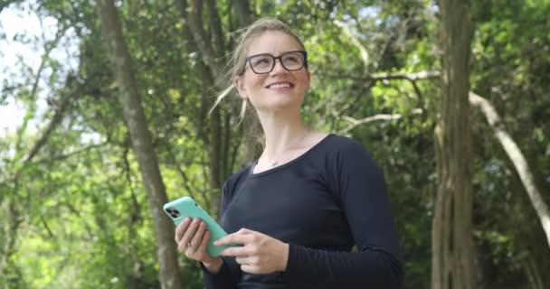 Mujer Blanca Joven Usando Teléfono Inteligente Durante Día Con Parque — Vídeos de Stock