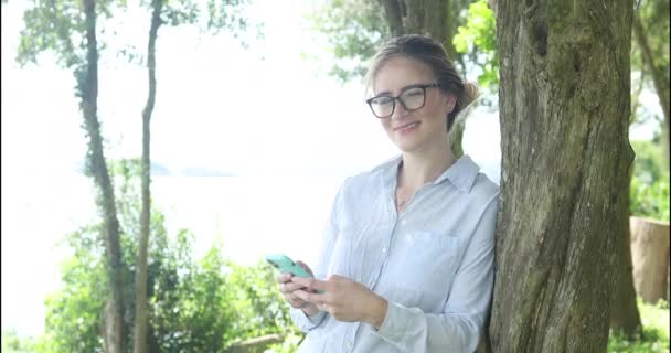 Mujer Blanca Joven Usando Teléfono Inteligente Durante Día Con Parque — Vídeos de Stock