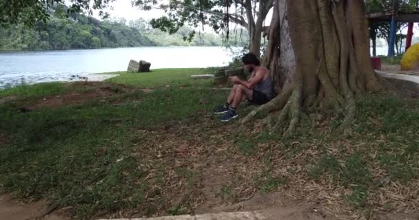 Молодий Чоловік Використовує Смартфон Вдень Зеленим Парком Задньому Плані — стокове відео