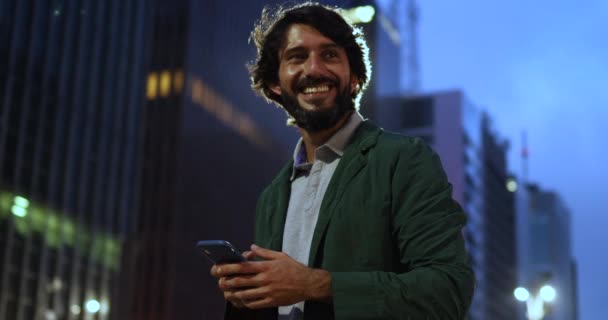 Arka Planda Şehir Manzarası Olan Gece Akıllı Telefon Kullanan Genç — Stok video