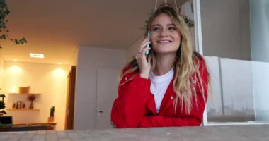 Genç bir kadın dairesinin balkonunda akıllı telefon kullanıyor. Yüksek kaliteli video. Cep telefonu, teknoloji, şehir kavramı.