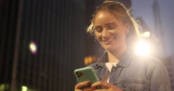 Νεαρή Γυναίκα Που Χρησιμοποιεί Ένα Smartphone Νύχτα Θέα Στην Πόλη — Αρχείο Βίντεο
