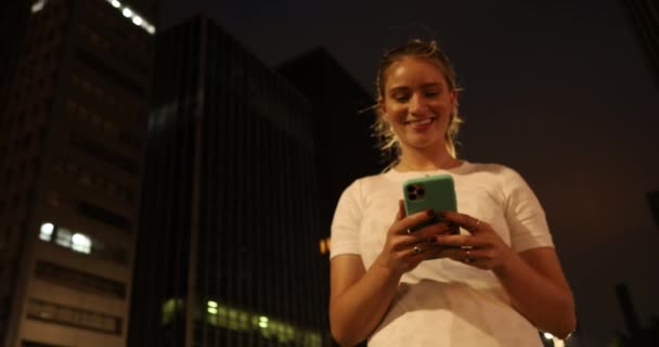 Nuori Nainen Käyttää Älypuhelinta Yöllä Kaupunkinäkymällä Maisema Taustalla — kuvapankkivideo