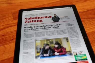 Solothurn, İsviçre, 03.01.2022: Tahta bir masa üzerine dijital bir gazete indirilmiş bir tablet.